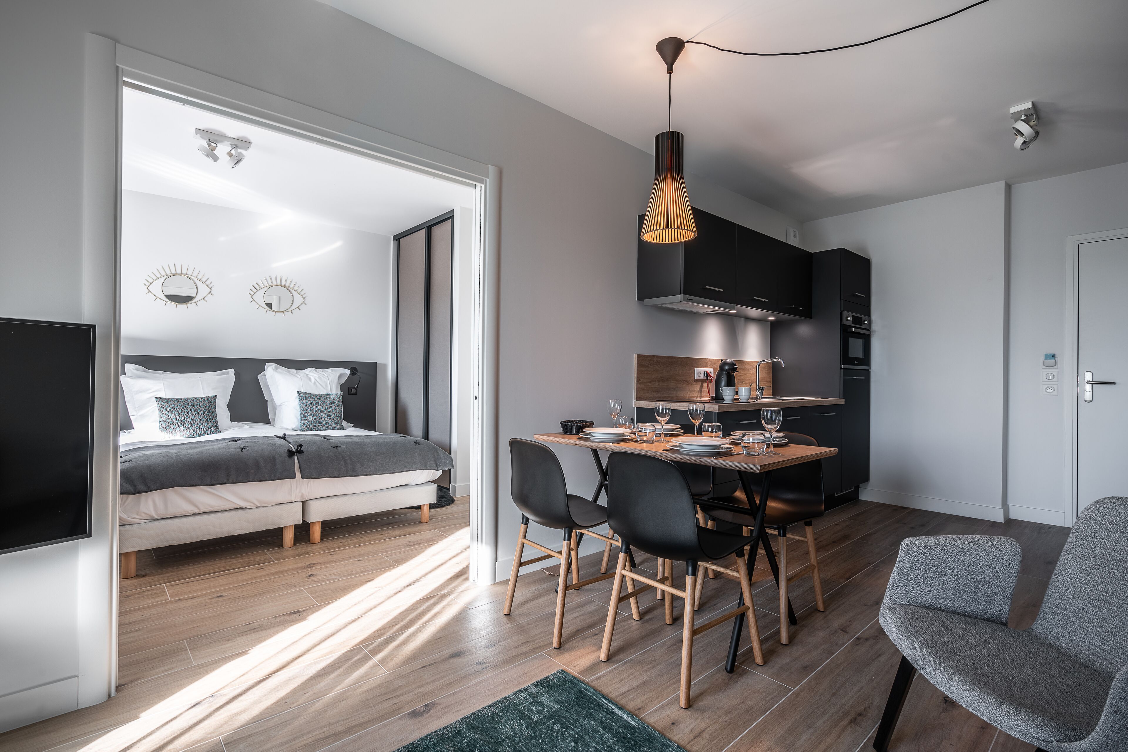 Un espacio habitable moderno y funcional con cama, zona de comedor y kitchenette.