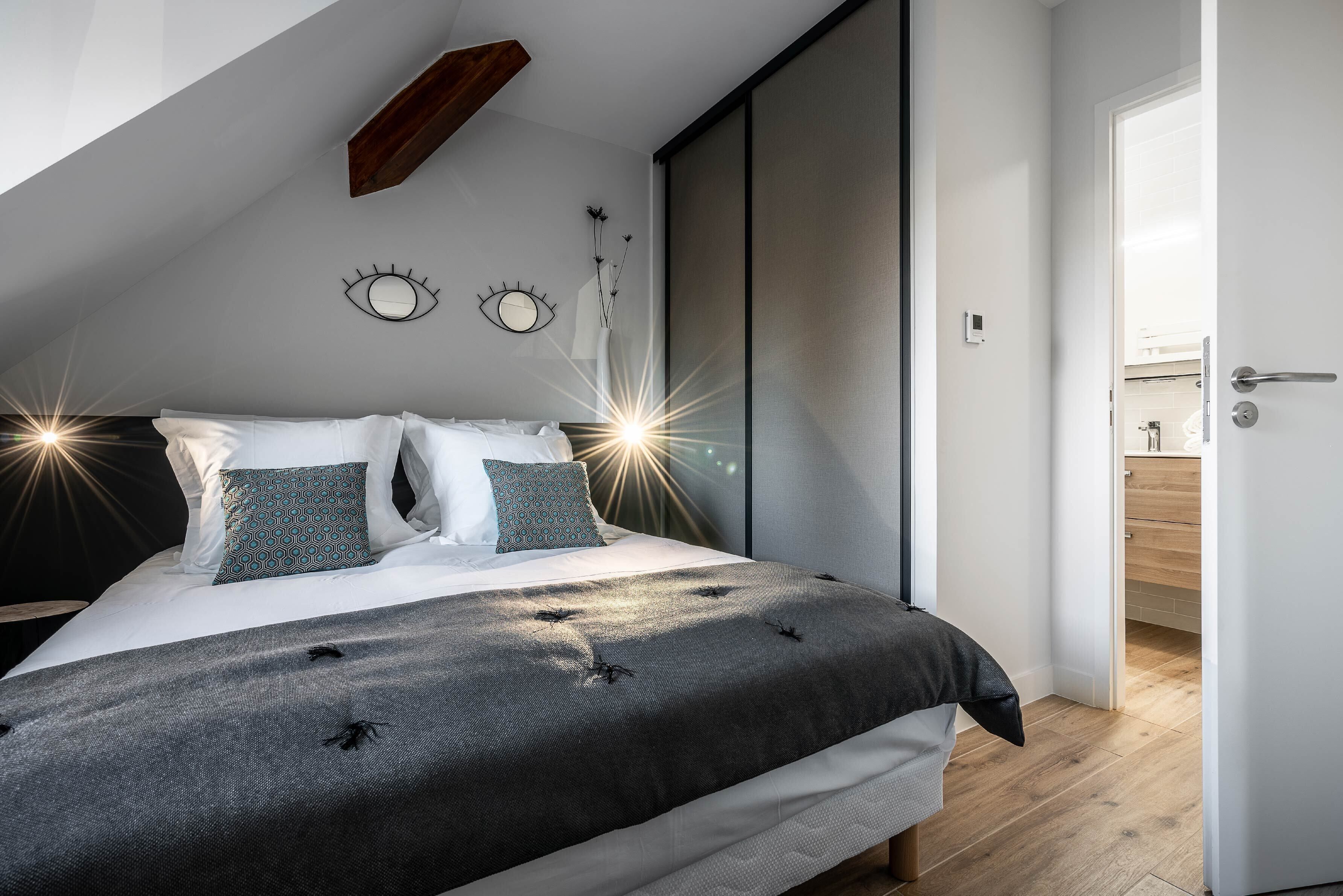 Ein modernes Schlafzimmer mit einem großen Bett, einem Oberlicht und Blick ins Bad.