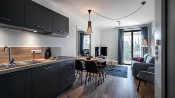 Een moderne keuken met donkere kasten, een houten aanrecht en een eethoek met een tafel en stoelen.