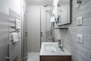 Un baño moderno con cabina de ducha de vidrio, un lavamanos blanco y un espejo grande.