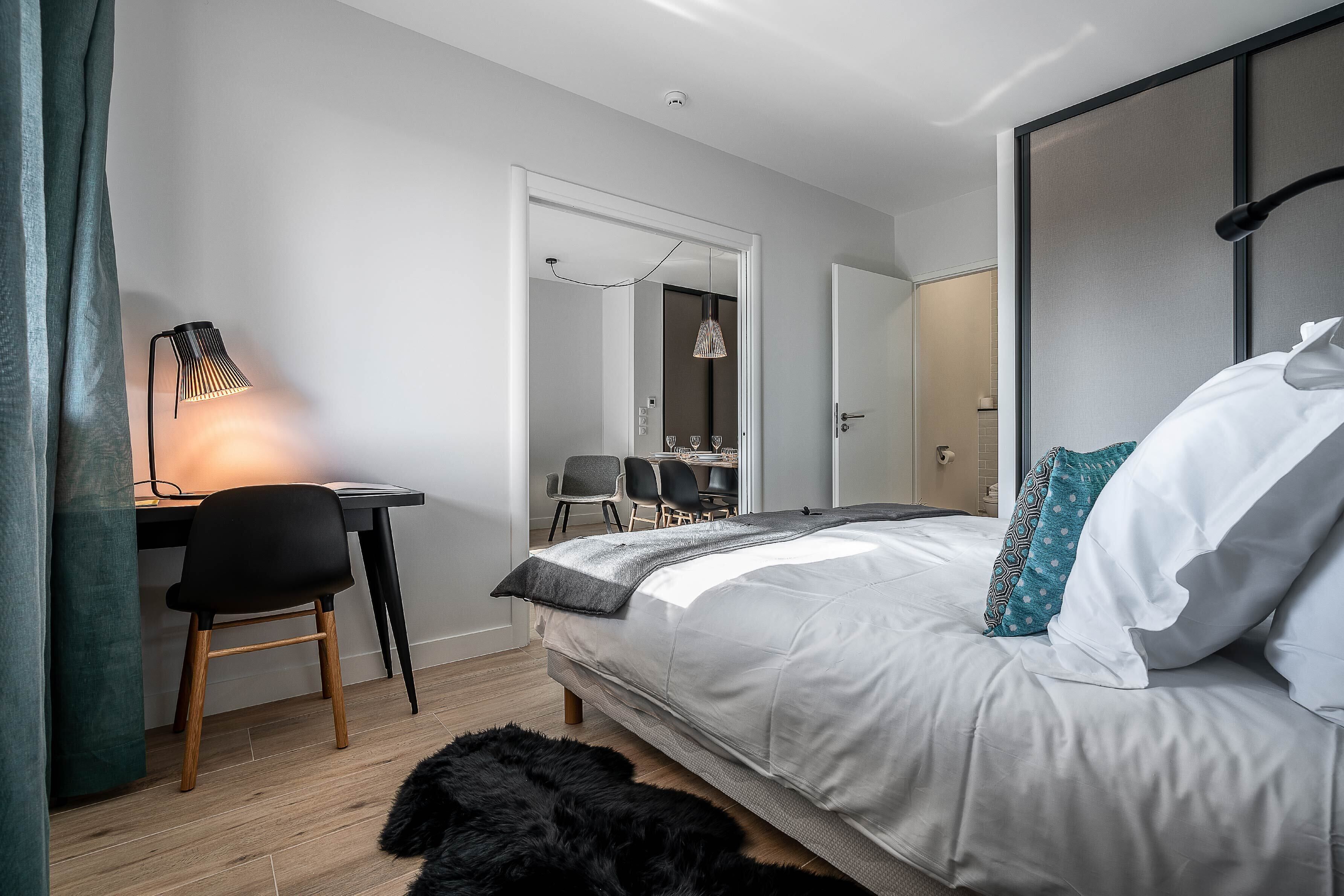 A modern bedroom with a bed, desk, and chair.