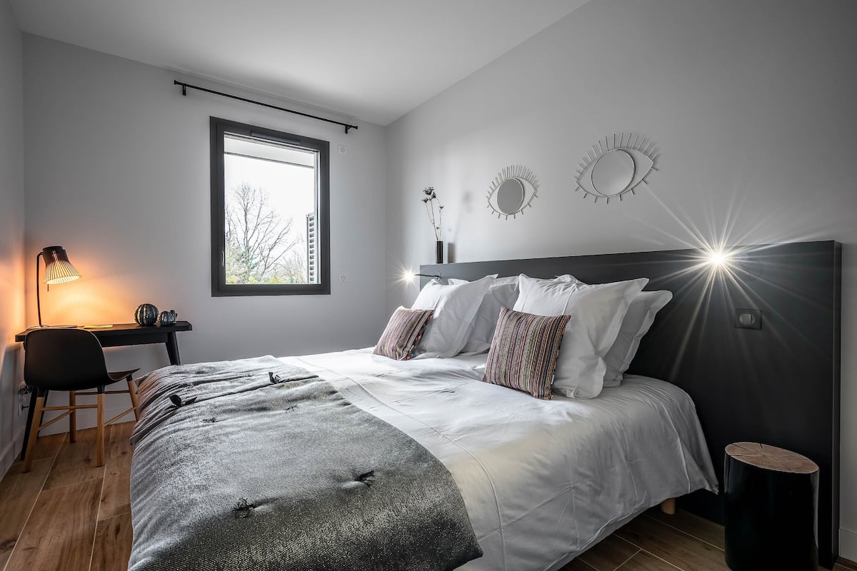 Une chambre à coucher avec un lit, une table de chevet, une lampe et une fenêtre.