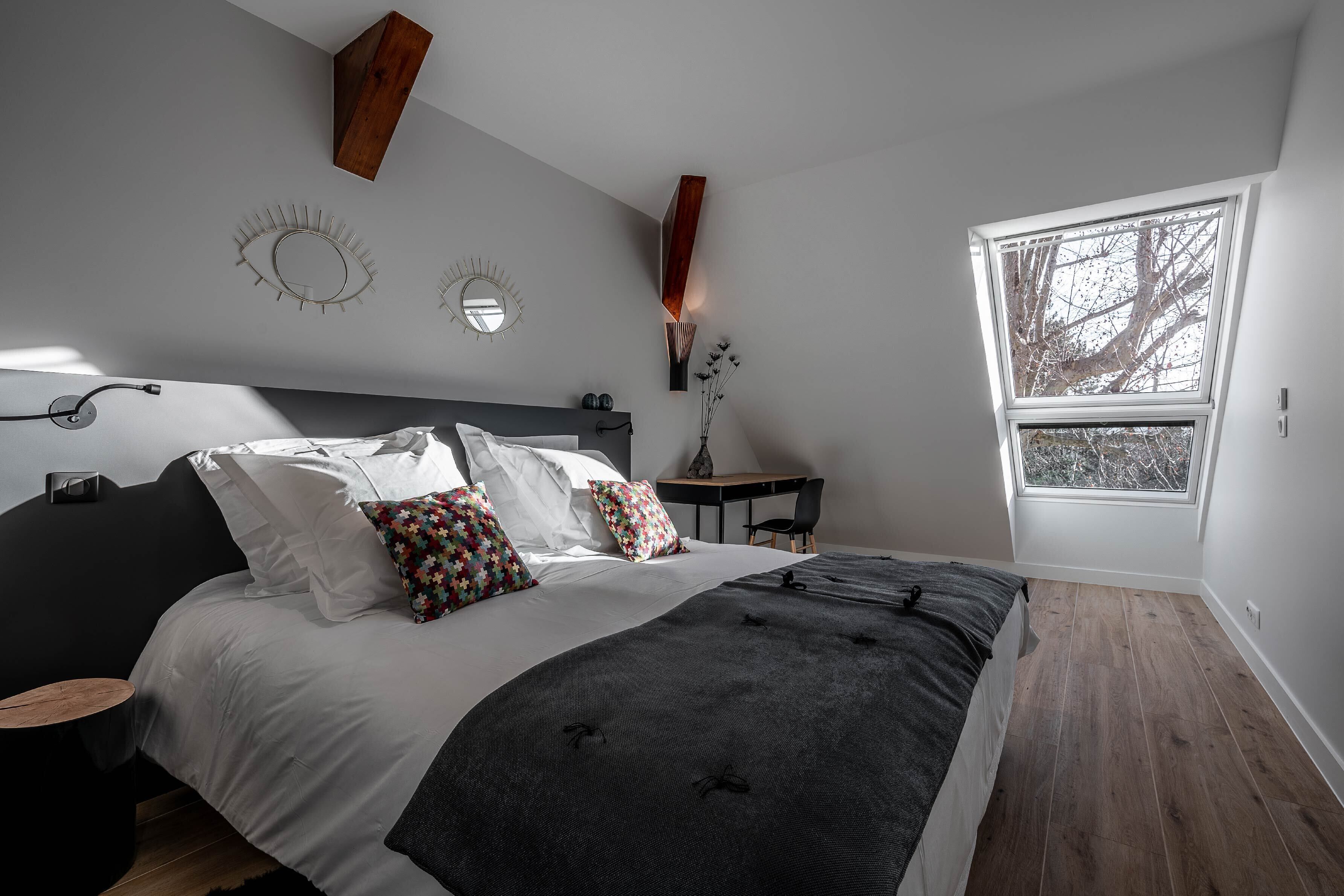 Een slaapkamer met een bed, nachtkastjes, een bureau en een raam.