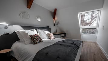 Een slaapkamer met een bed, nachtkastjes, een bureau en een raam.