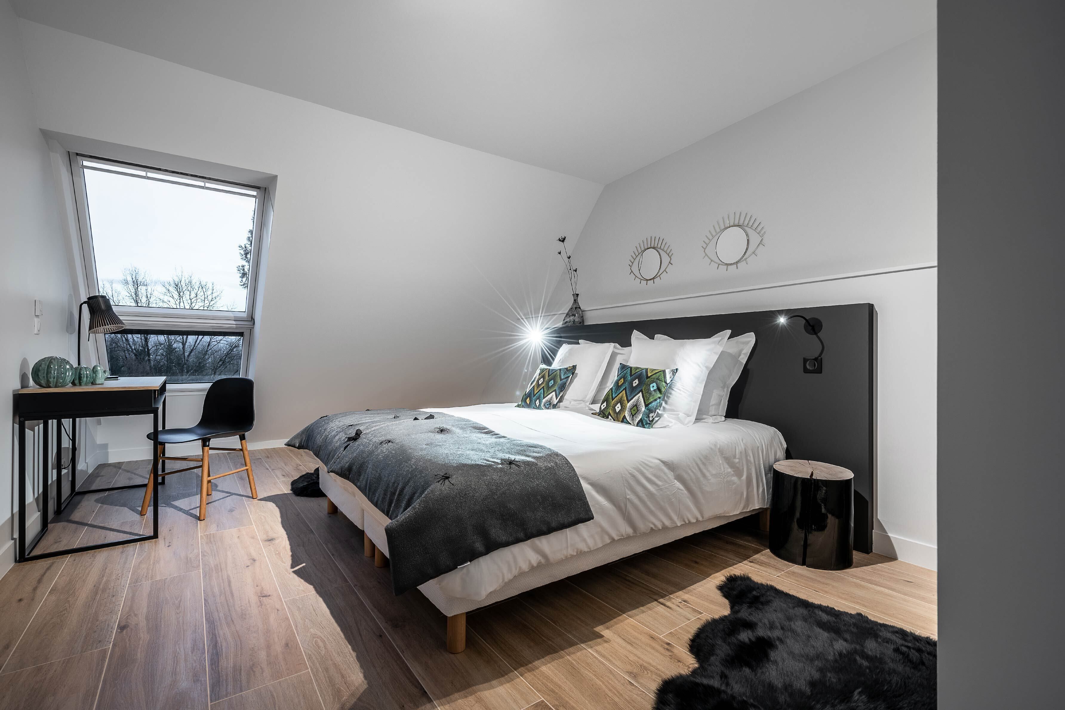 Une chambre à coucher moderne avec un grand lit, un bureau et une chaise.