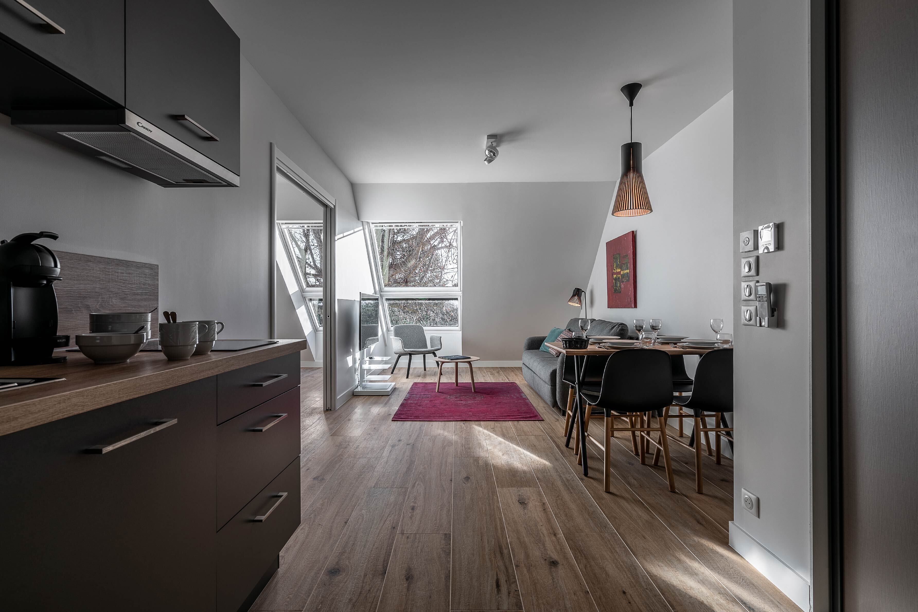 Una cucina moderna con zona pranzo, pavimento in legno e vista panoramica tramite una porta vetrata.