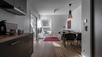 Una cucina moderna con zona pranzo, pavimento in legno e vista panoramica tramite una porta vetrata.