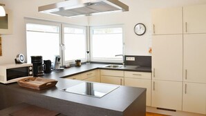 Una cocina moderna con una isla central, microondas, cafetera y un reloj en la pared.