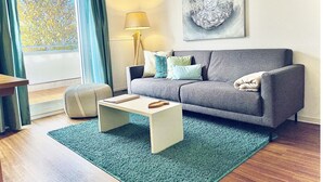 Una sala de estar moderna con un sofá gris, una mesa de centro blanca y un tapete azul.