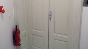 Een witte deur met een zilveren handgreep en een rode brandblusser aan de linker muur bevestigd.