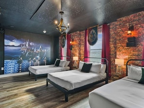 A hotel room with two beds, a brick wall, a mural, and a chandelier.