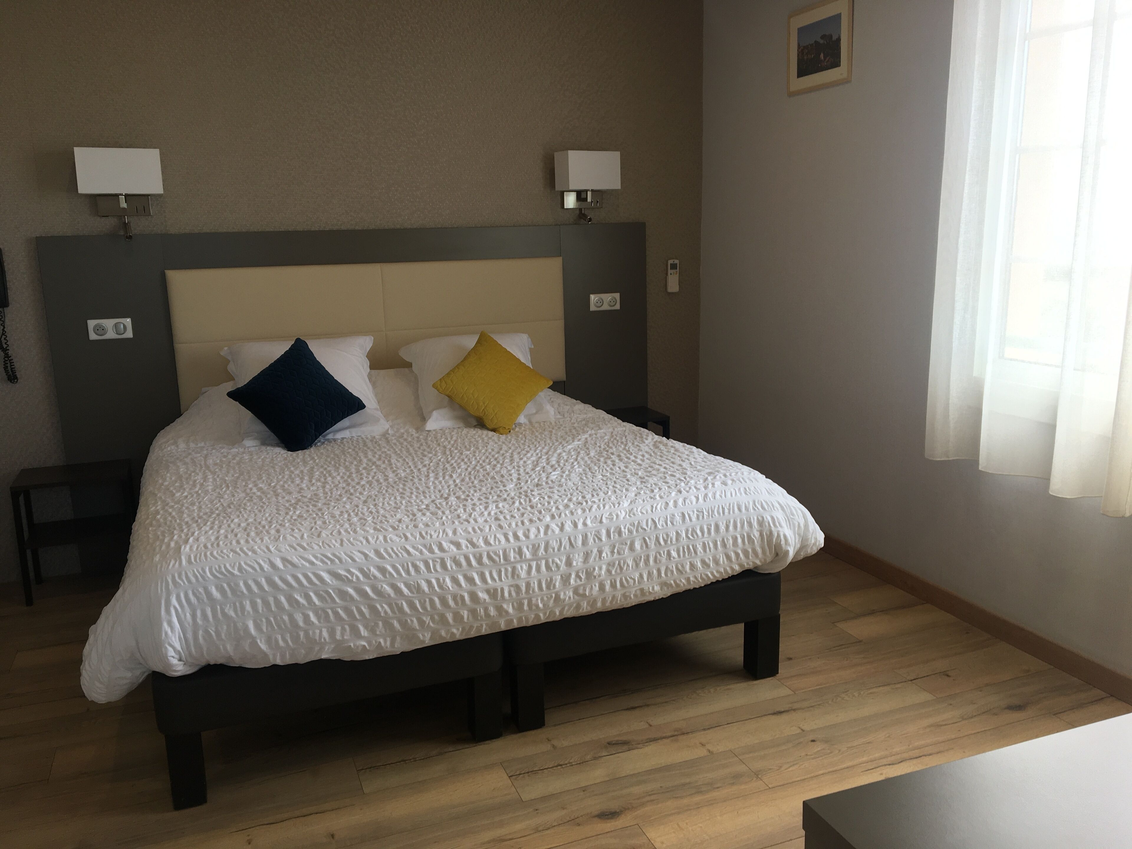 A neatly made bed with a white quilt, two bedside lamps, and a small bedside table.