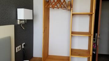 A bedroom with a wooden wardrobe, a bedside table, a lamp, and a bed.
