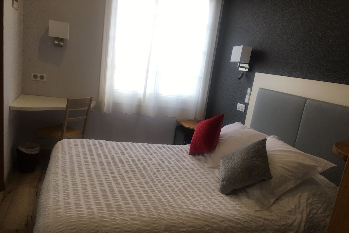 Um quarto com uma cama, uma escrivaninha e uma cadeira.