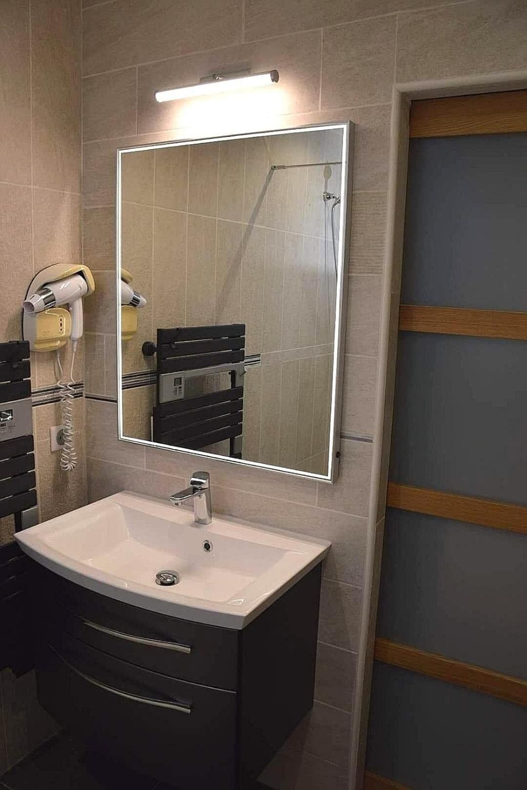 Un baño con un espejo grande, un lavabo y una ducha.