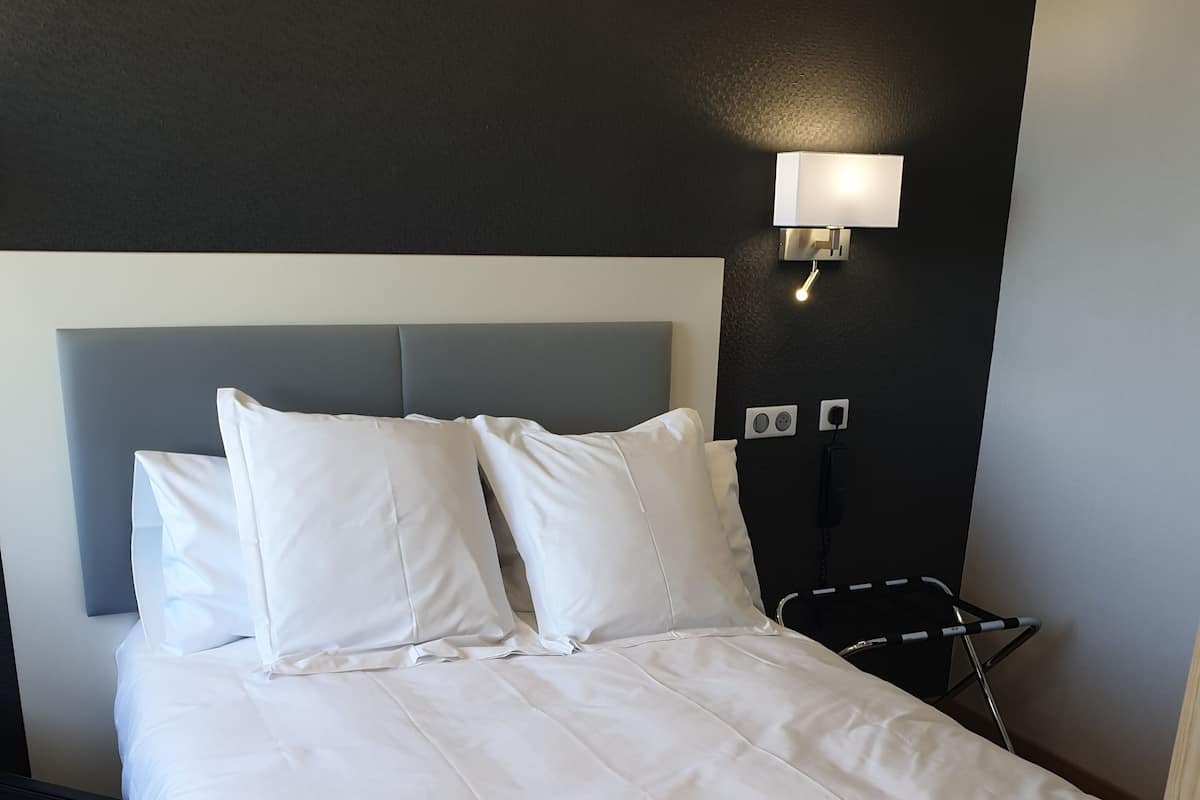 Cama bem arrumada com lençóis brancos em um quarto de hotel.