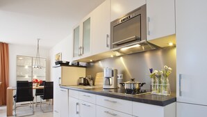 A modern kitchen with white cabinets, a built-in microwave, and a coffee maker. - Wohnung 3 (Norderney)
