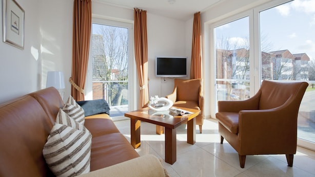 A modern living room with a sofa, armchair, and a coffee table. - Wohnung 3 (Norderney)