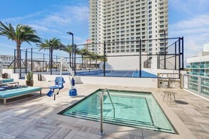 A rooftop pool area with lounge chairs, a tennis court, and a view of a tall building. - Bay views, luxury finishes, and coastal chic in this 1-bedroom heaven (Miami)