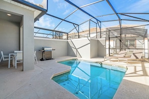 An indoor swimming pool with a glass ceiling, surrounded by lounge chairs and a barbecue area. - 5-BR Townhouse with Pool & Theme room Near Disney (Kissimmee)