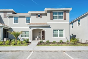 A two-story residential building with a front entrance, a driveway, and a well-maintained lawn. - 5-BR Townhouse with Pool & Theme room Near Disney (Kissimmee)