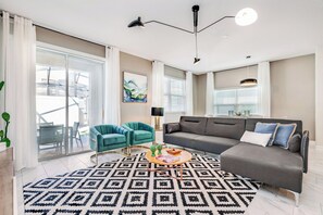 A modern living room with a sofa, two armchairs, a coffee table, and a patterned rug.