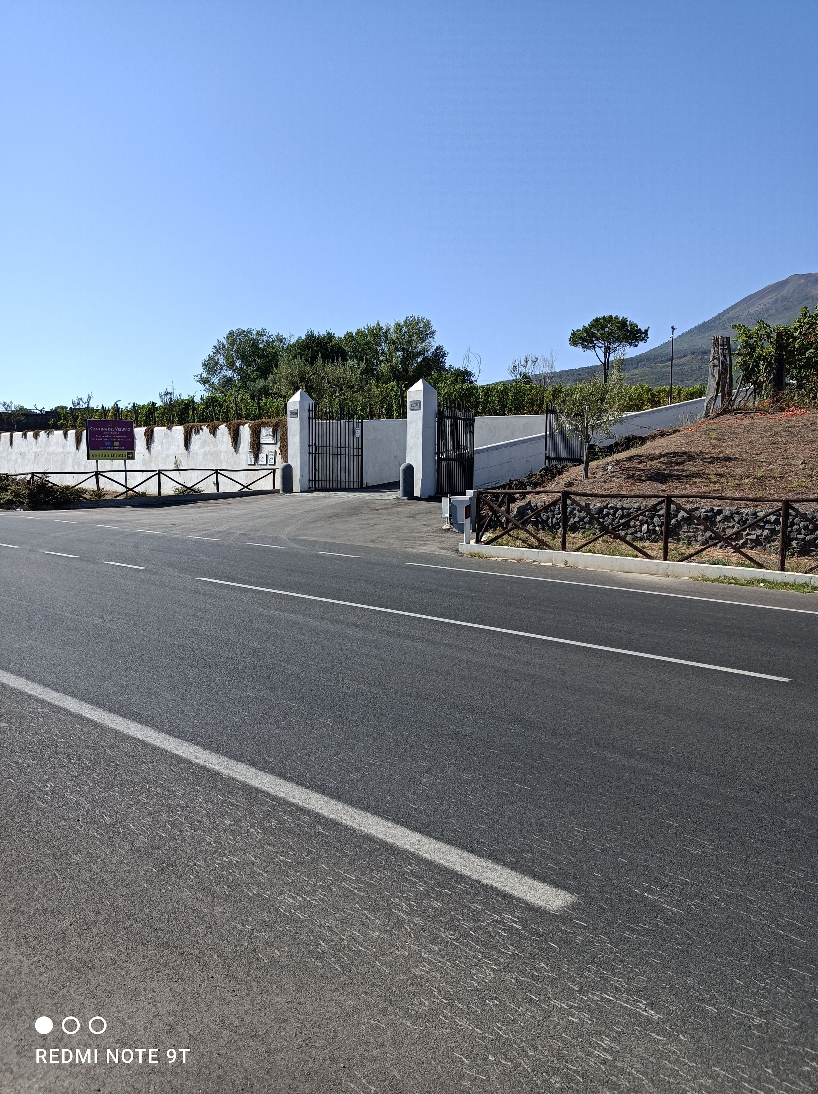 A road leading to a gated entrance with a sign indicating a parking area.
