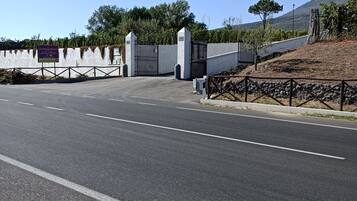 A road leading to a gated entrance with a sign indicating a parking area.