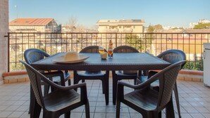 Ein Balkon mit Tisch und Stühlen, einer Flasche und einem Bierglas.