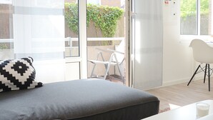 A bedroom with a bed, a chair, a table, and a view of the outside. - Wohnung Gartenstraße 23 (Norderney)