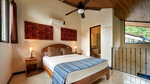 Una camera da letto con un letto di legno, due comodini con lampade e un ventilatore a soffitto, con vista sull'esterno attraverso una finestra.