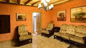 A room with a patterned floor, a wooden ceiling, and a chandelier. There are three upholstered chairs and a sofa. - "Casa Rural La Cuca" (Lerín)