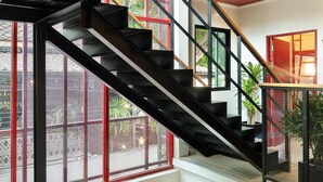 Um interior em vários níveis, com escada, guarda-corpos de metal e janelas amplas.