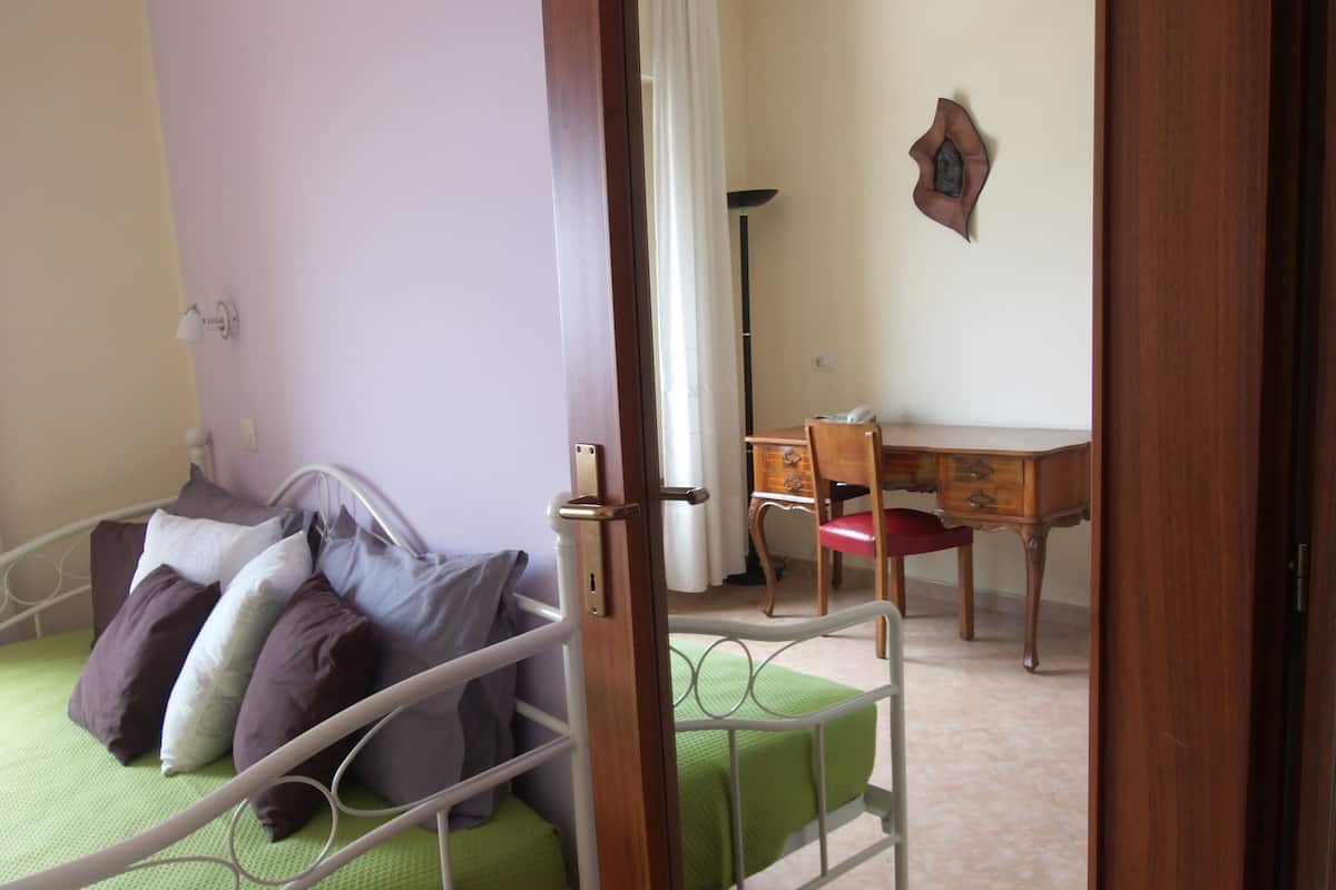 Een slaapkamer met een bed, een bureau en een stoel.