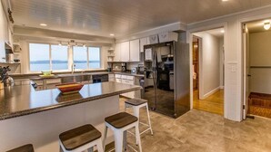 Una cocina moderna con una isla grande, electrodomésticos de acero inoxidable y vistas al exterior.