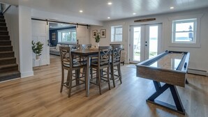 Amplia habitación con mesa de billar, suelo de madera y una escalera que conduce a otra zona.