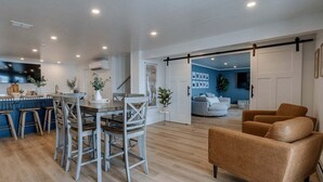 Un interior moderno con zona de comedor, sofá y puerta corredera que da a otra habitación.