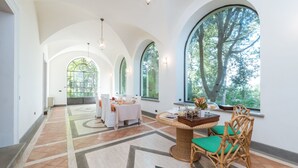 A spacious room with high ceilings and large arched windows overlooking a forest. - Borgo Colle Ridente 13, Emma Villas (Camerino)