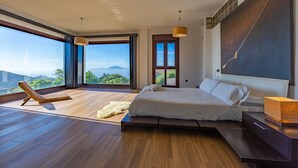 Un dormitorio moderno con una cama grande, un sillón de descanso y vistas a la montaña.