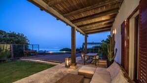 Un patio al aire libre con zona de estar acolchada, una mesa y un farol.