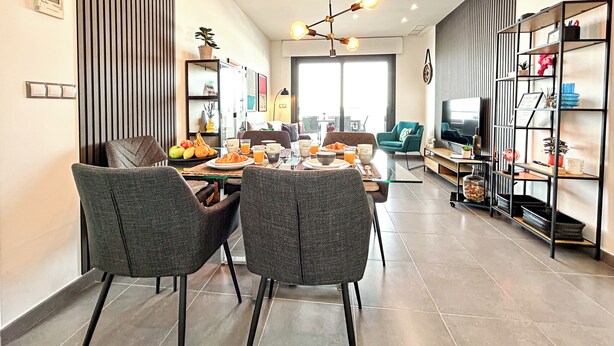 A modern living room with a dining area, featuring a sofa, a coffee table, and a TV. - Myflats Luxury Arenales (Elche)