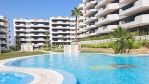 A modern hotel with a swimming pool, multiple balconies, and a well-maintained garden area. - Myflats Luxury Arenales (Elche)