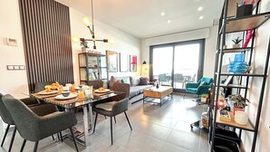A modern living room with a dining area, a sofa, a coffee table, and a bookshelf. - Myflats Luxury Arenales (Elche)