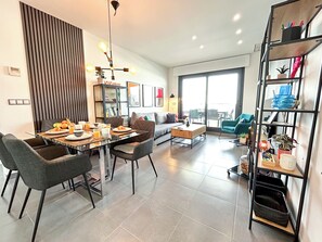 A modern living room with a dining area, a sofa, a coffee table, and a bookshelf. - Myflats Luxury Arenales (Elche)