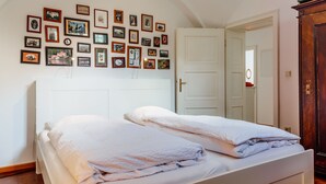 A bedroom with two beds, a wall of framed pictures, and a wooden wardrobe.