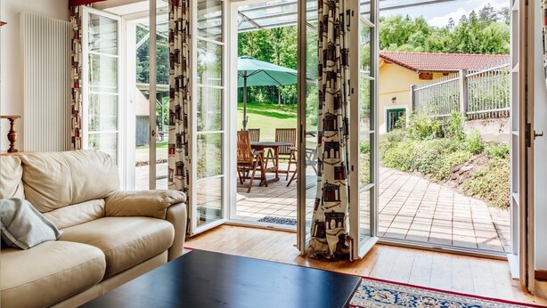 A living room with a beige sofa, a black coffee table, and a view of a patio with a table and chairs.
