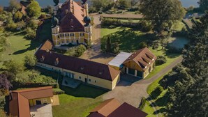An aerial view of a large estate with multiple buildings, including a main house with a red roof and several smaller structures.