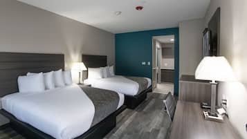 Une chambre d’hôtel avec deux lits, un bureau, une chaise, une lampe et un miroir.