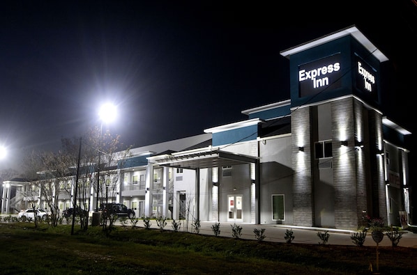 Un hotel moderno con un llamativo letrero Express Inn, estacionamiento techado y una entrada bien iluminada.