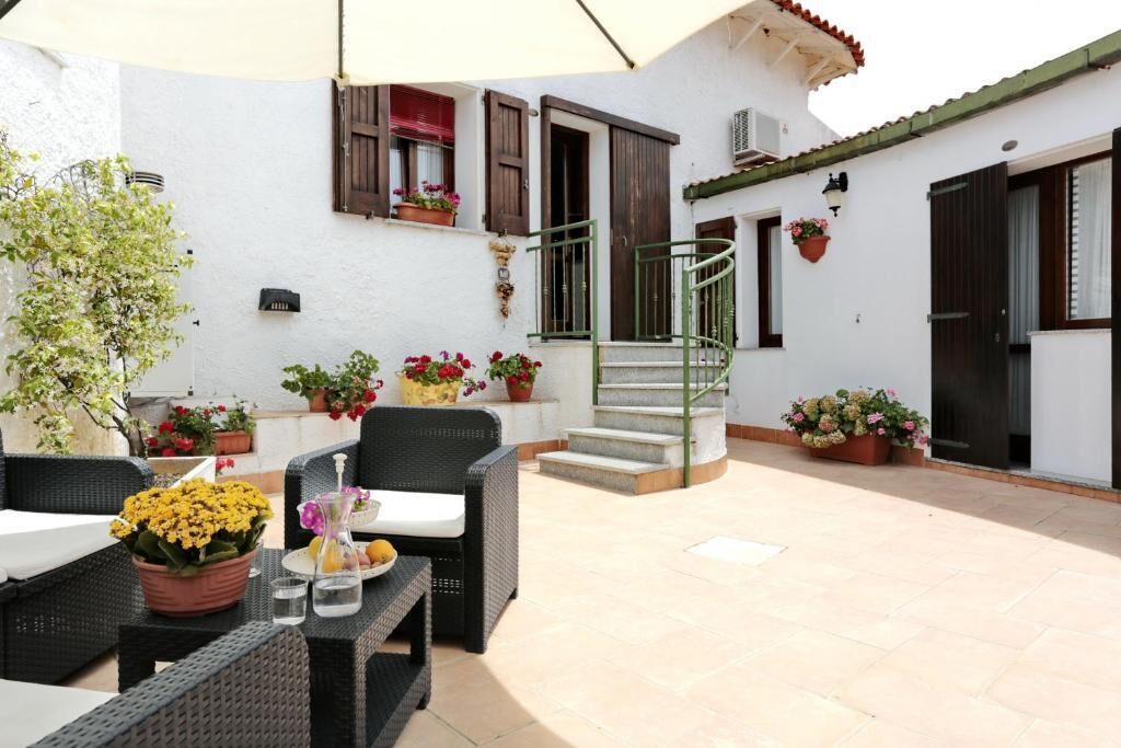 Un espace patio aménagé avec des meubles en osier, des plantes en pot et un escalier en colimaçon.